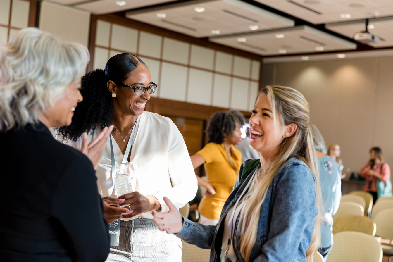 Mature adult female conference speaker laughs with mid adult women